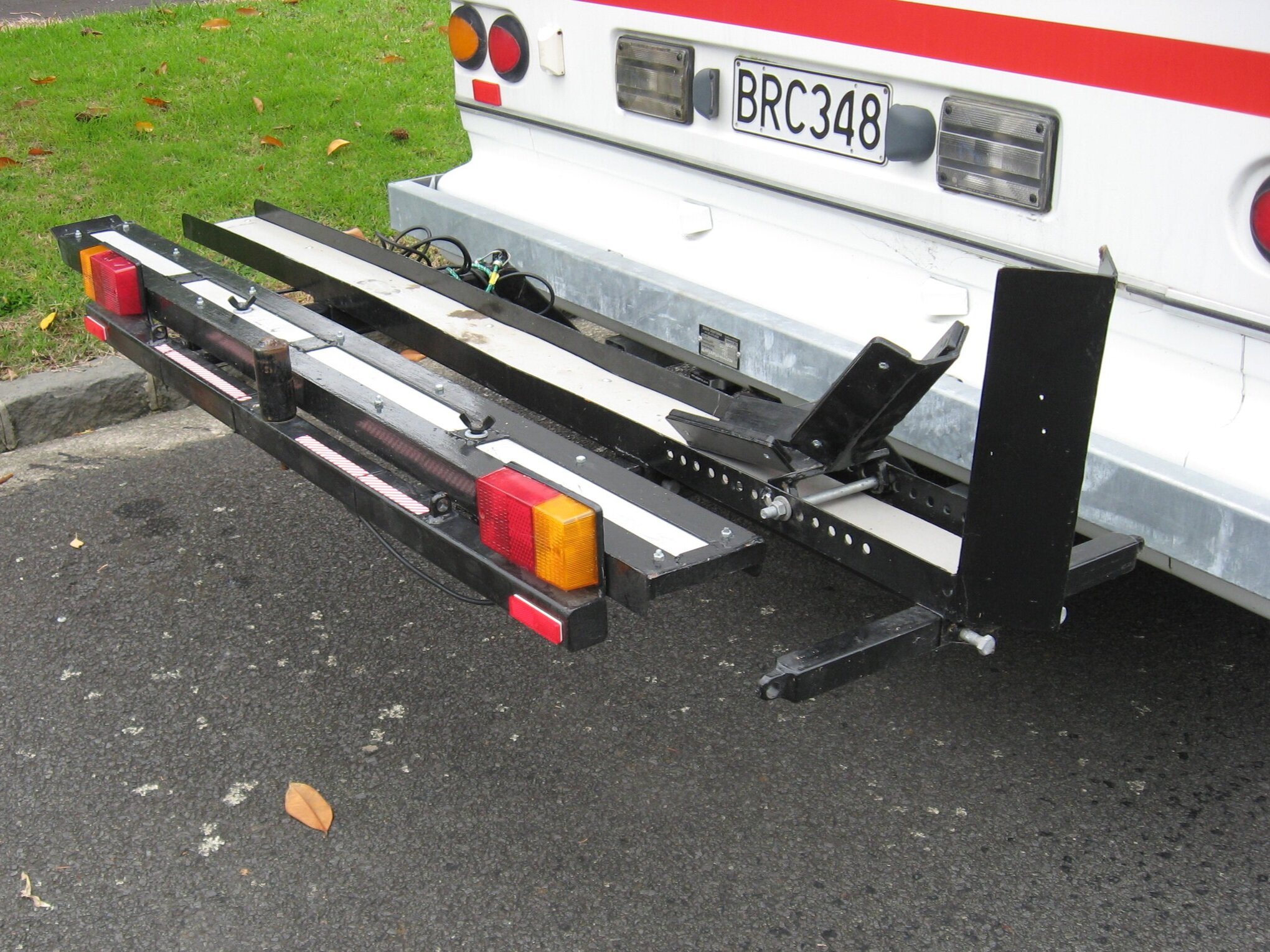 Scooter carrier in place, with pivoting wheel clamp. Note ramp held upside down with bolts topped by wing nuts